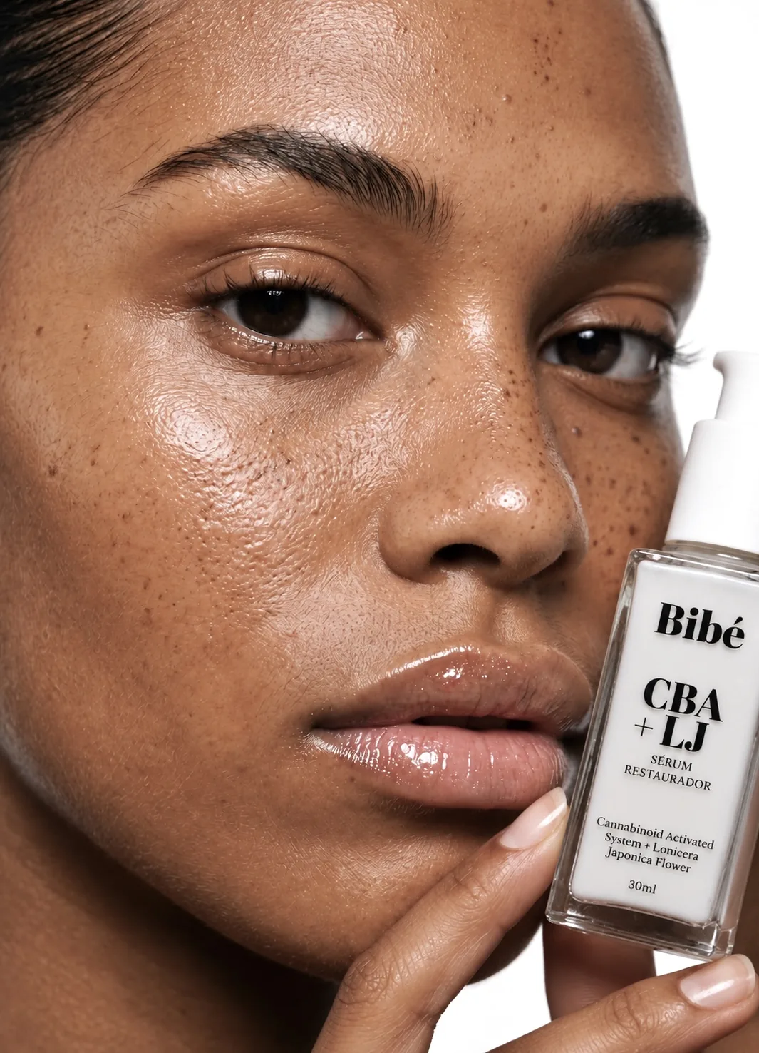 Model with hair in a bun holding a Bibé serum bottle near her neck
