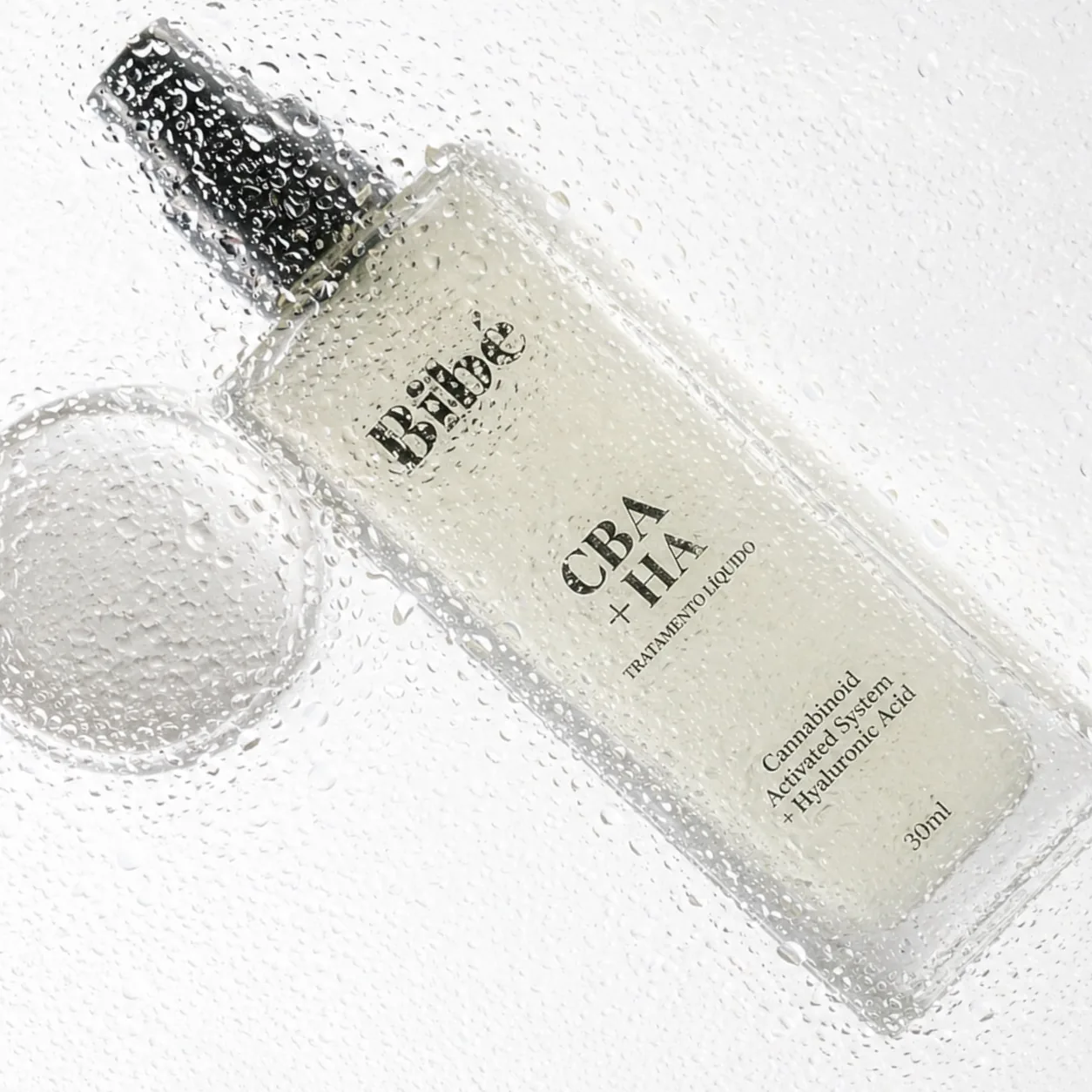 Bibé lip oil bottle on its side amid water droplets