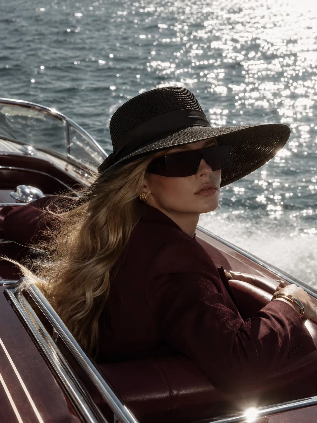 Lucky Girl Syndrome campaign: model in a black hat looking back over her shoulder on a yacht